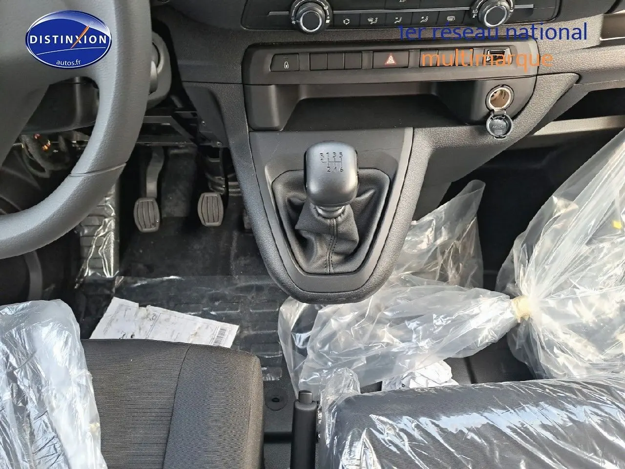 Vue rapprochée de l'intérieur du Peugeot Expert cabine approfondie 2023, montrant la boîte manuelle et les sièges noirs protégés.