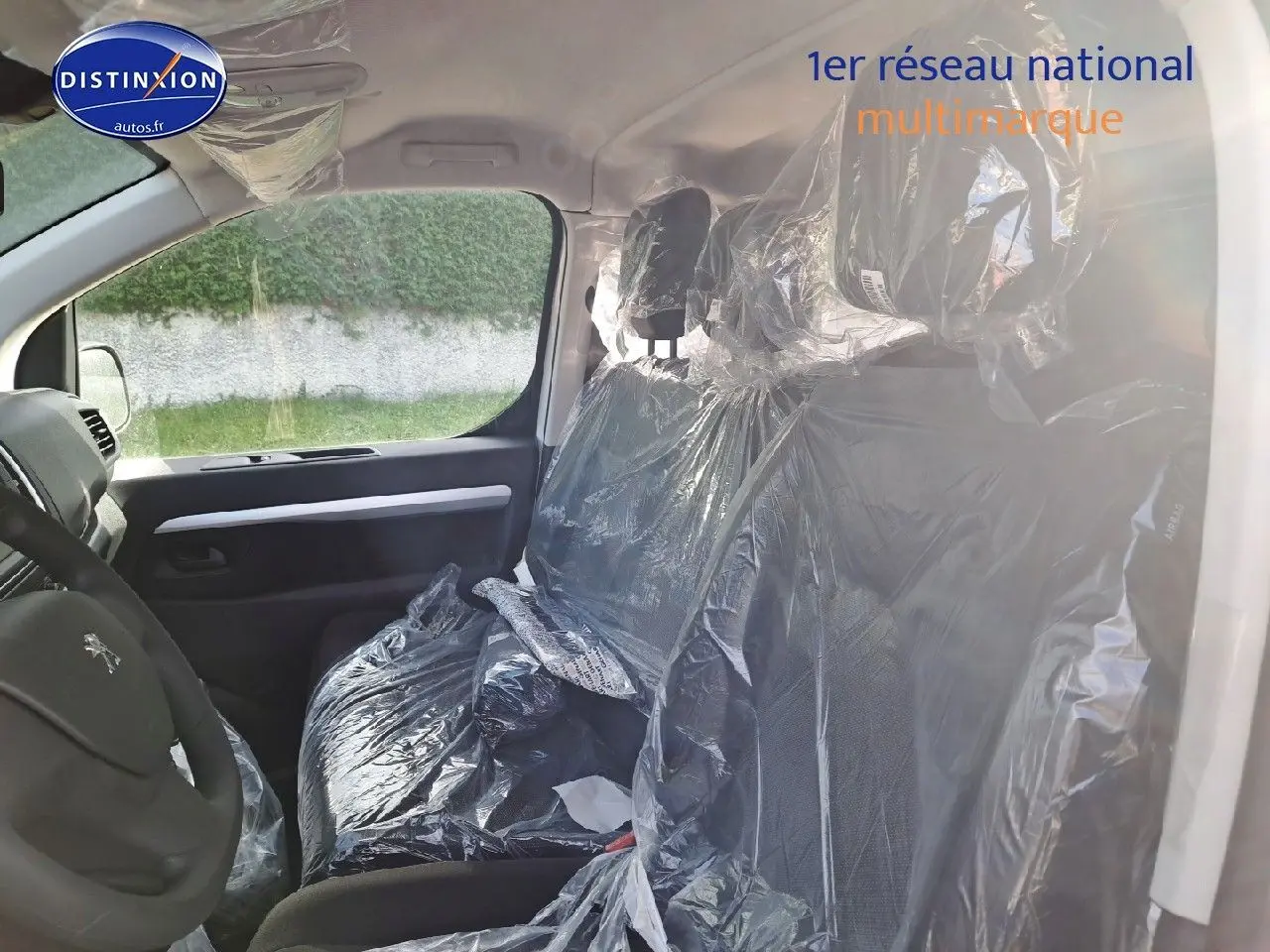 Vue intérieure côté conducteur du Peugeot Expert Cabine Approfondie 2023, sièges noirs encore protégés par des housses plastiques.