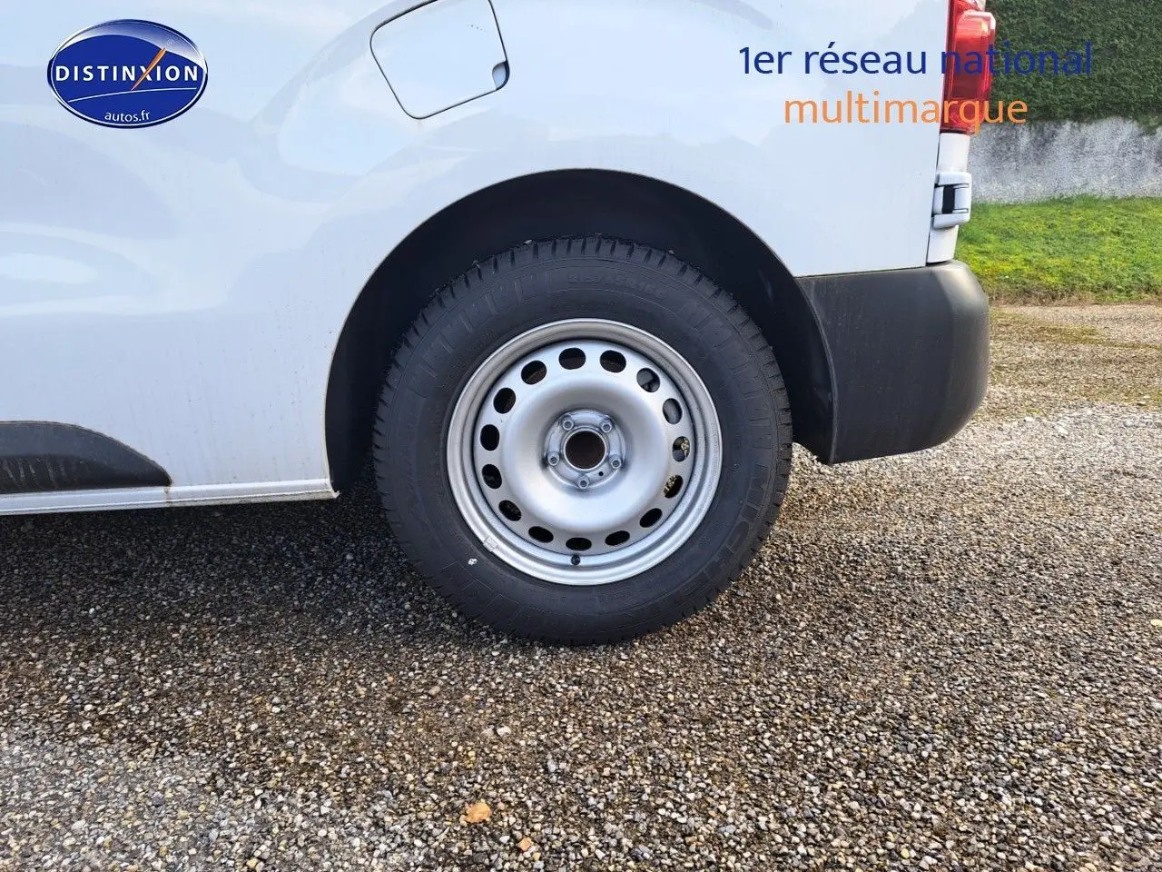 Gros plan sur la roue arrière droite d’un Peugeot Expert Blanc Kaolin, avec pare-chocs noir et carrosserie visible.