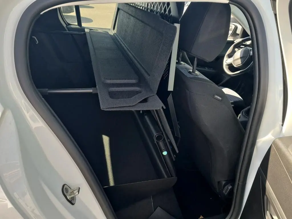 Vue intérieure côté gauche de la Peugeot 208 Affaire blanche, montrant la banquette rabattue et la grille de séparation.