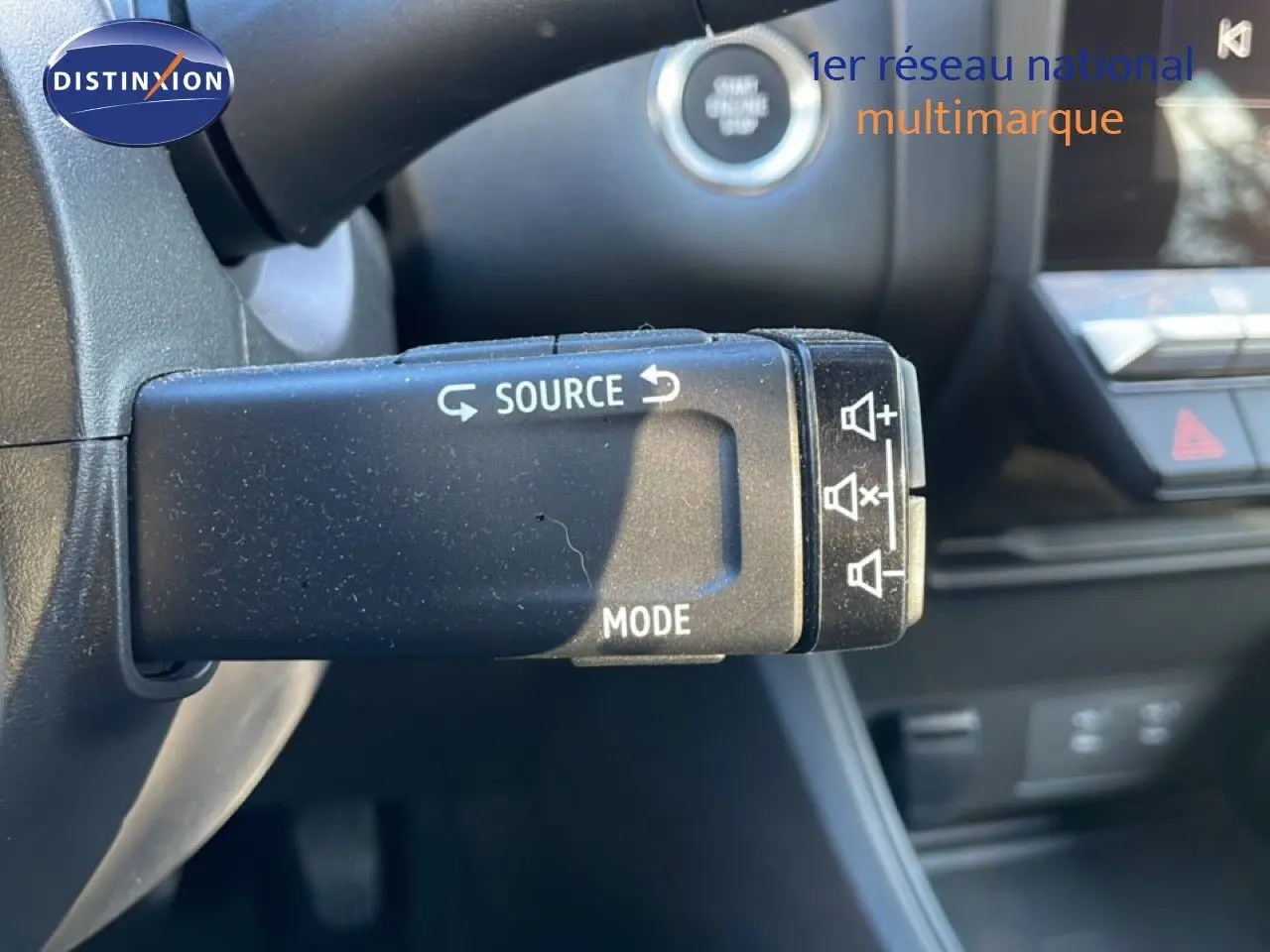 Gros plan sur la commande au volant du Renault Captur 2025 gris Rafale métal avec toit noir, montrant les boutons source et mode.