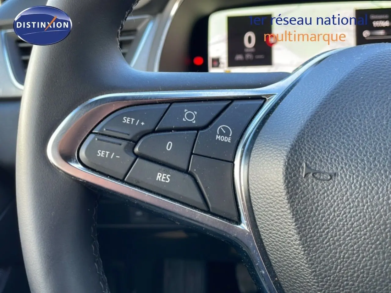 Gros plan sur les commandes au volant côté gauche du Renault Captur gris Rafale métal 2025 avec affichage numérique en arrière-plan.