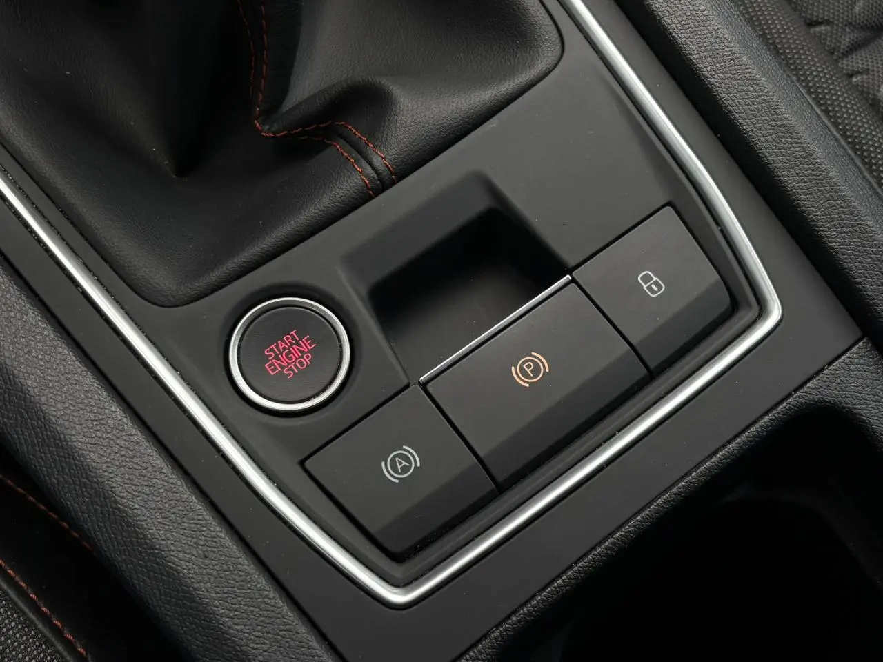 Gros plan sur la console centrale noire du SEAT Leon 2025, avec bouton Start Engine Stop et commandes électroniques.