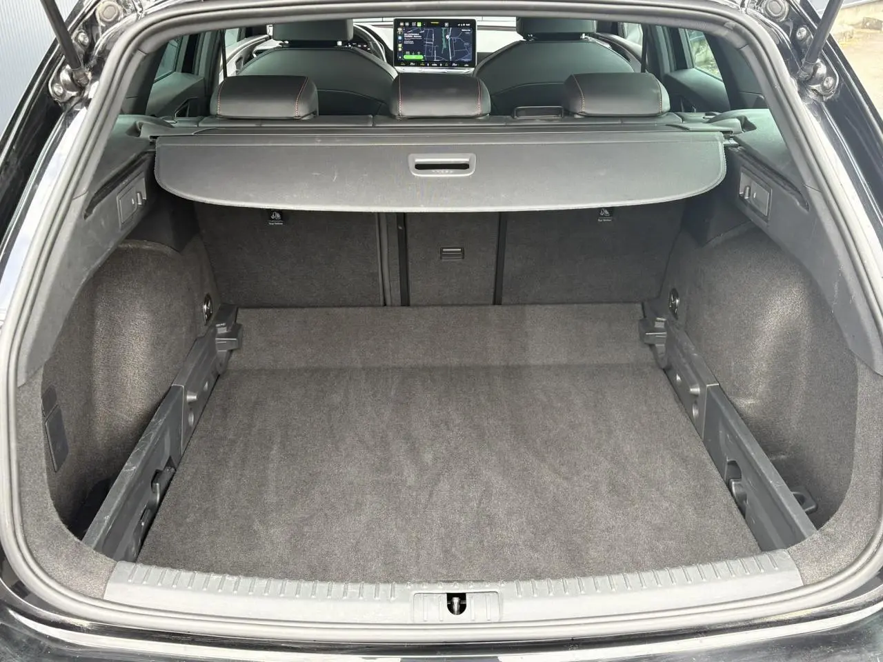 Coffre ouvert vu de l'arrière d'une SEAT Leon 2025 Noir Minuit, avec cache-bagages et sièges arrière visibles.