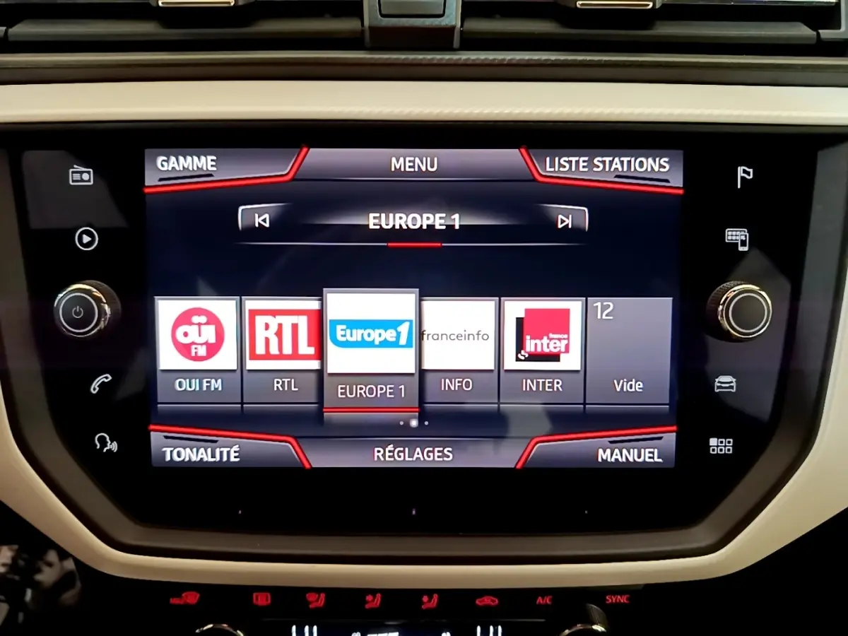 Écran tactile central du tableau de bord du SEAT Arona 2019 affichant les stations radio, entouré de commandes physiques.