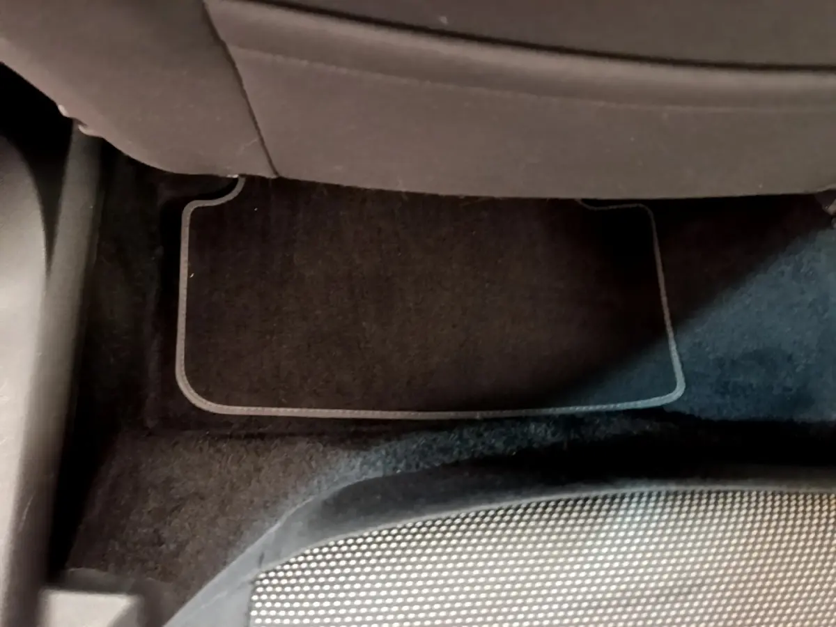 Vue rapprochée du tapis de sol noir sous le siège arrière du SEAT Arona gris clair, intérieur sobre.
