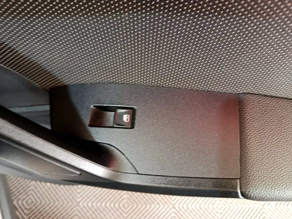 Gros plan sur le bouton de verrouillage des portes côté intérieur d'une SEAT Arona gris clair.