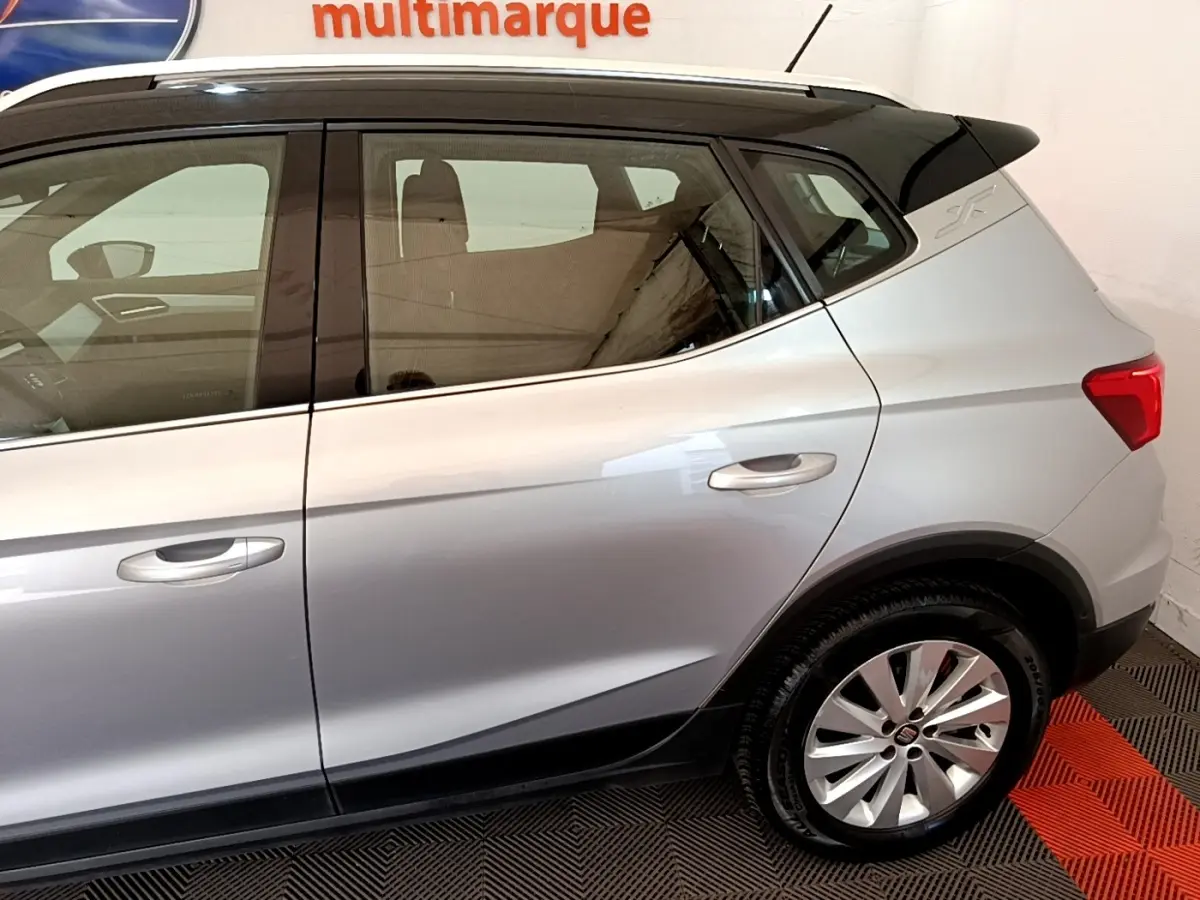 Vue latérale droite d'un SEAT Arona gris clair avec jantes alliage et toit noir contrasté.