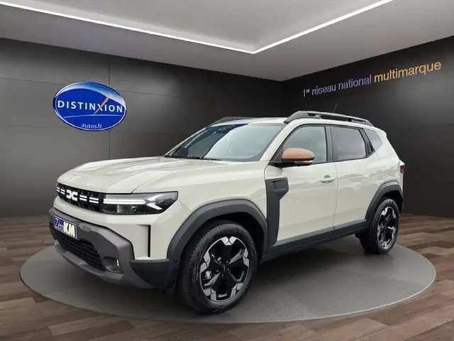 Vue 3/4 avant droite d'un Dacia Duster blanc avec jantes alu noires et coques de rétroviseurs couleur cuivre.