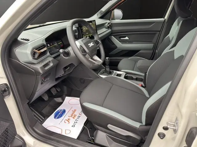 Intérieur avant droit du Dacia Duster 2025, sièges noirs, volant simili cuir, tableau de bord moderne avec écran tactile.