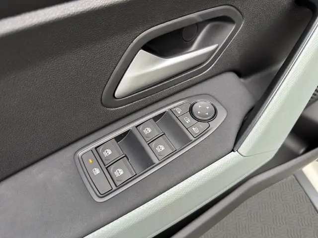 Gros plan sur la commande des vitres électriques côté gauche d'une Dacia Duster 2025, garniture noire et poignée argentée.