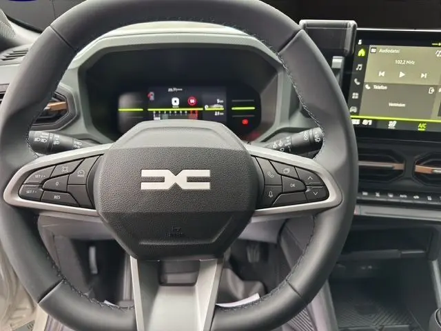 Vue rapprochée du volant noir multifonction du Dacia Duster 2025 avec tableau de bord numérique et écran central tactile.