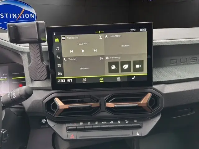 Tableau de bord du Dacia Duster 2025 avec écran tactile central et aérateurs noirs et cuivrés, ambiance intérieure moderne.
