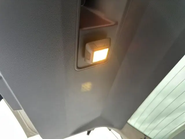 Plafonnier intérieur allumé sur le toit noir du Dacia Duster 2025, vue en légère contre-plongée côté arrière.