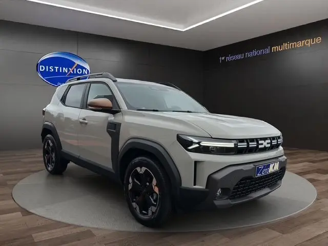 Dacia Duster 2025 beige vue 3/4 avant droit avec jantes alu noires et rétroviseurs couleur cuivre en showroom