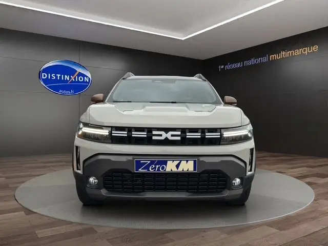 Vue frontale du Dacia Duster 2025 blanc, mettant en valeur la calandre moderne et les feux LED horizontaux.