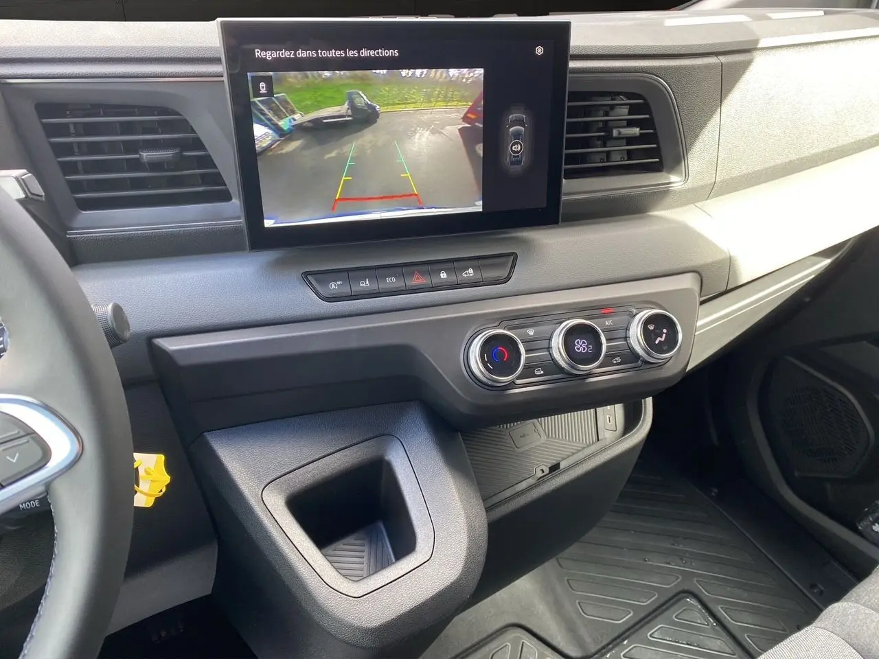 Vue intérieure côté conducteur du tableau de bord gris du Renault Master 2025 avec écran de recul et commandes de climatisation.