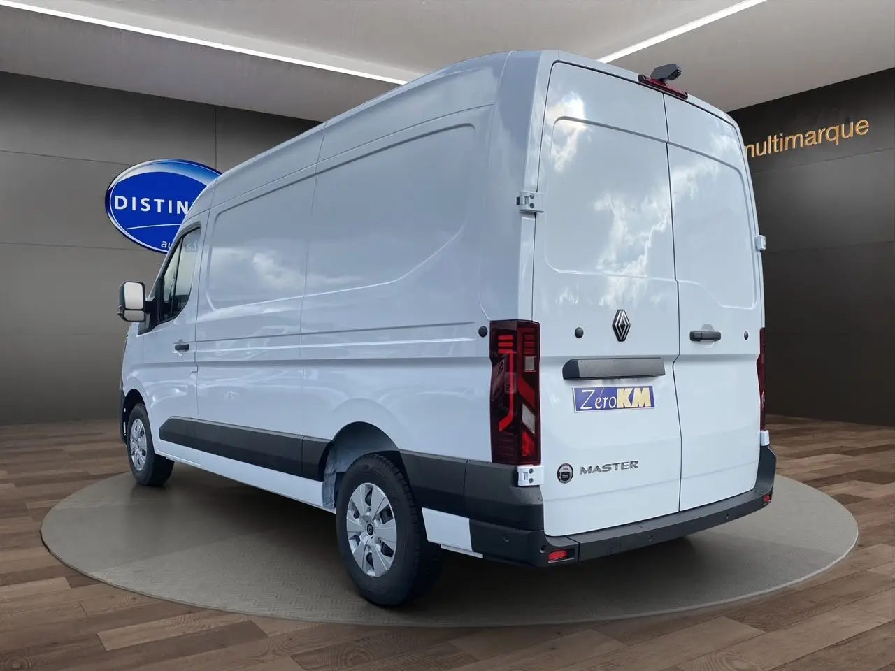 Renault Master blanc en 3/4 arrière droit, fourgon utilitaire avec feux arrière verticaux et bande noire latérale.