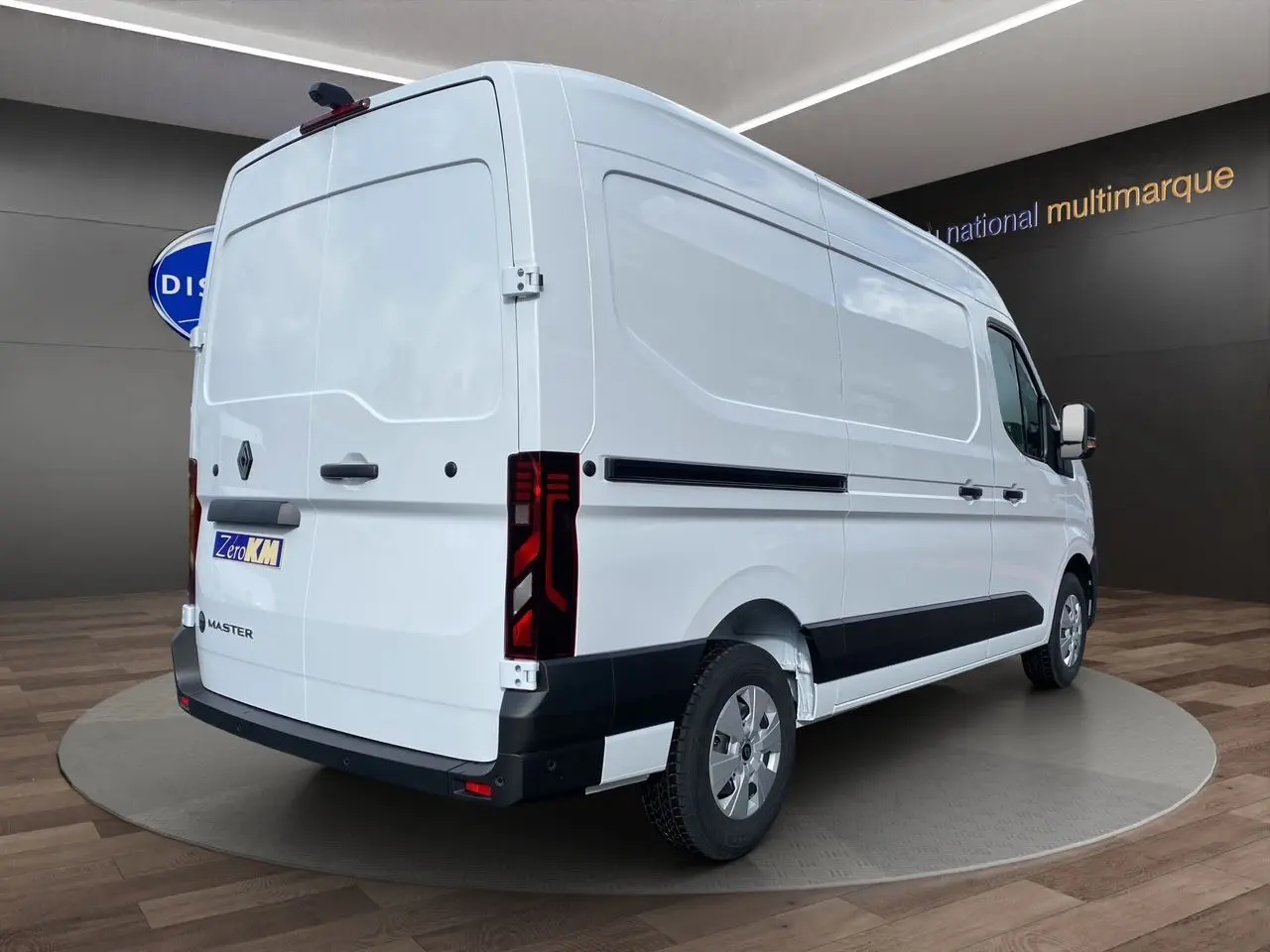 Renault Master blanc en vue 3/4 arrière droit, fourgon utilitaire avec feux arrière verticaux et protections noires.
