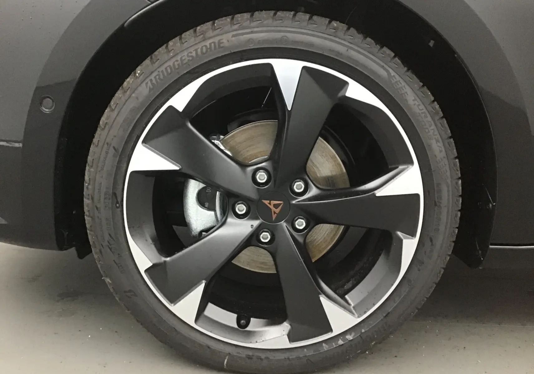 Gros plan sur la jante noire et argentée de 18 pouces avec logo Cupra sur un véhicule noir.