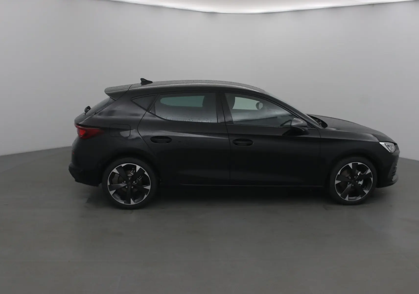 Profil côté gauche d'une CUPRA Leon noire 2023 avec jantes alliage et lignes sportives marquées.