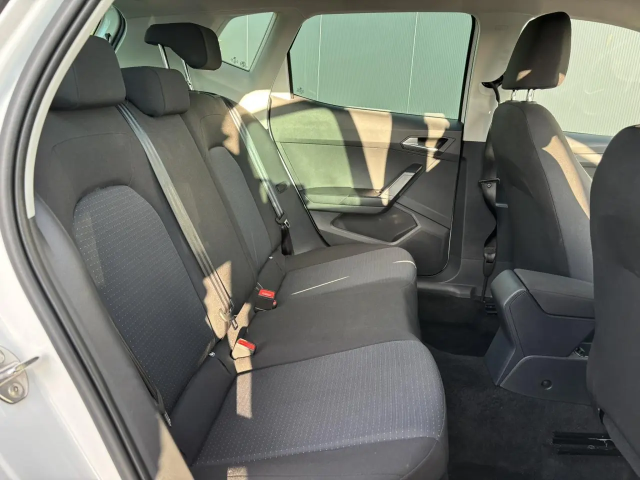 Vue intérieure côté gauche des sièges arrière noirs du SEAT Arona blanc, mettant en valeur l'espace et les ceintures de sécurité.