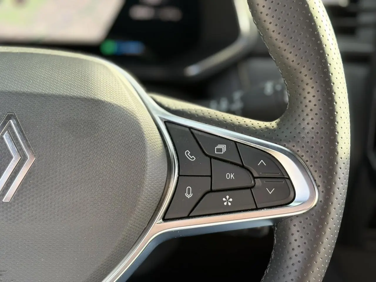 Gros plan sur le volant en cuir perforé gris du Renault Symbioz E-Tech 2025 avec commandes multifonctions à droite.