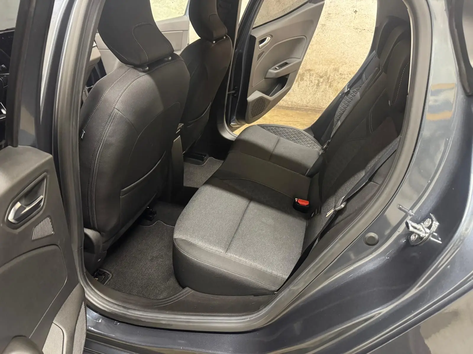 Vue intérieure côté arrière droit de la Renault Clio V Business 2019 gris titanium, montrant les sièges arrière en tissu noir.