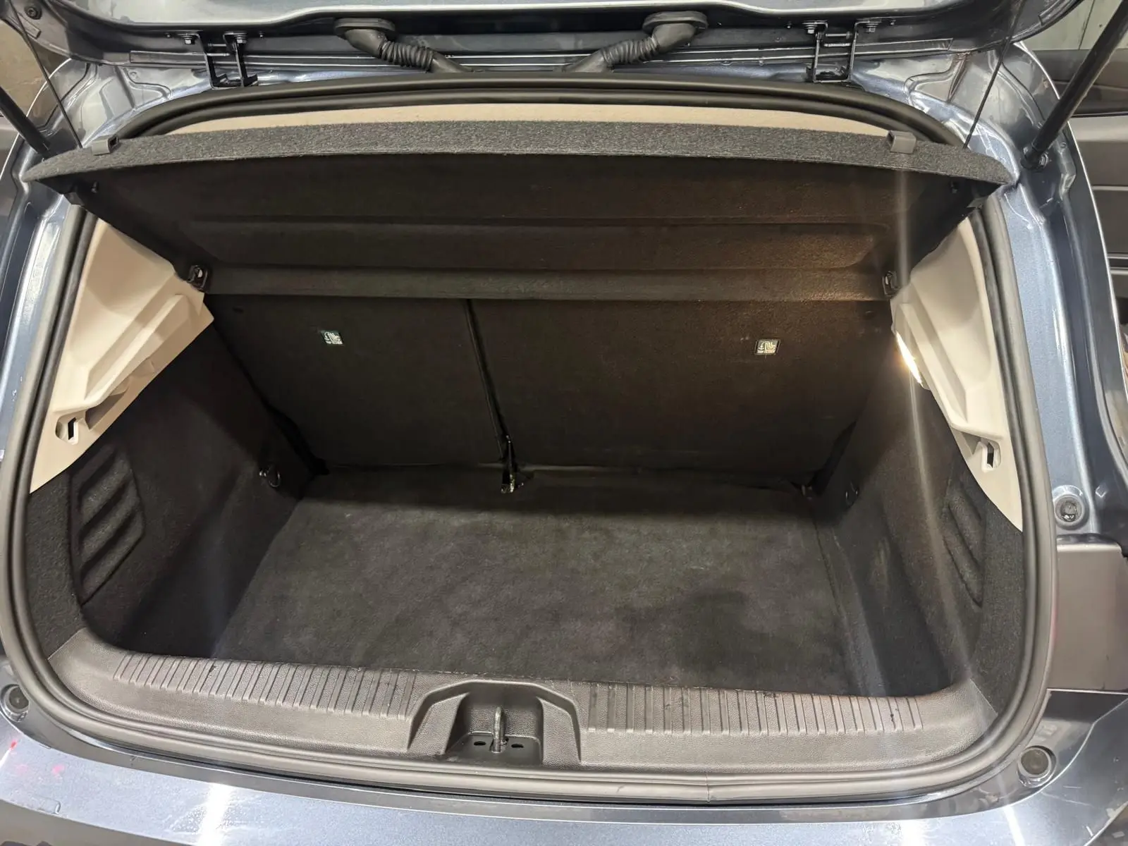Coffre ouvert vu de l'arrière d'une Renault Clio V Business gris titanium, montrant l'espace de chargement vide et propre.