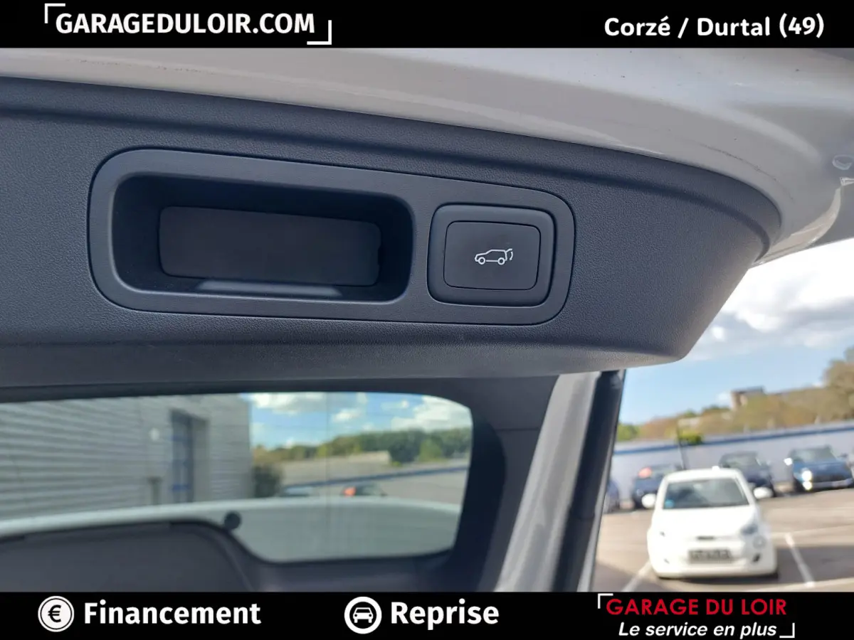 Détail intérieur du hayon ouvert du MG MOTOR EHS 2025, bouton de fermeture électrique visible sur fond clair.