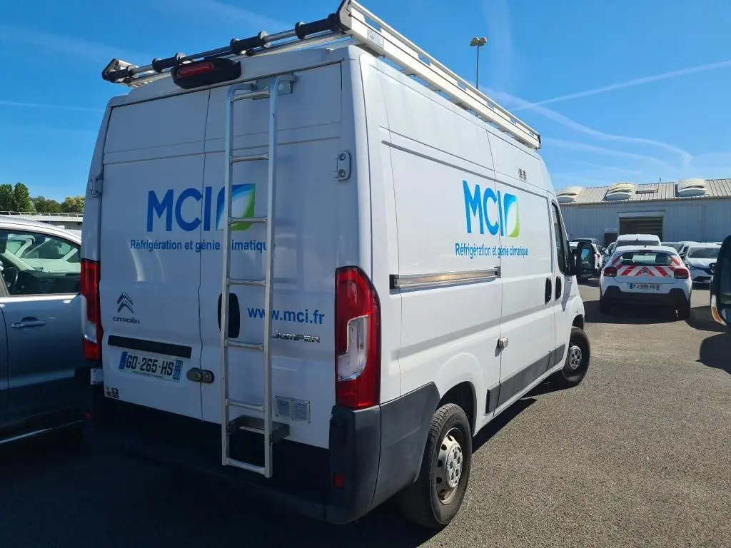 Vue 3/4 arrière droite d’un Citroën Jumper blanc avec galerie, échelle et logo MCI sur la carrosserie.