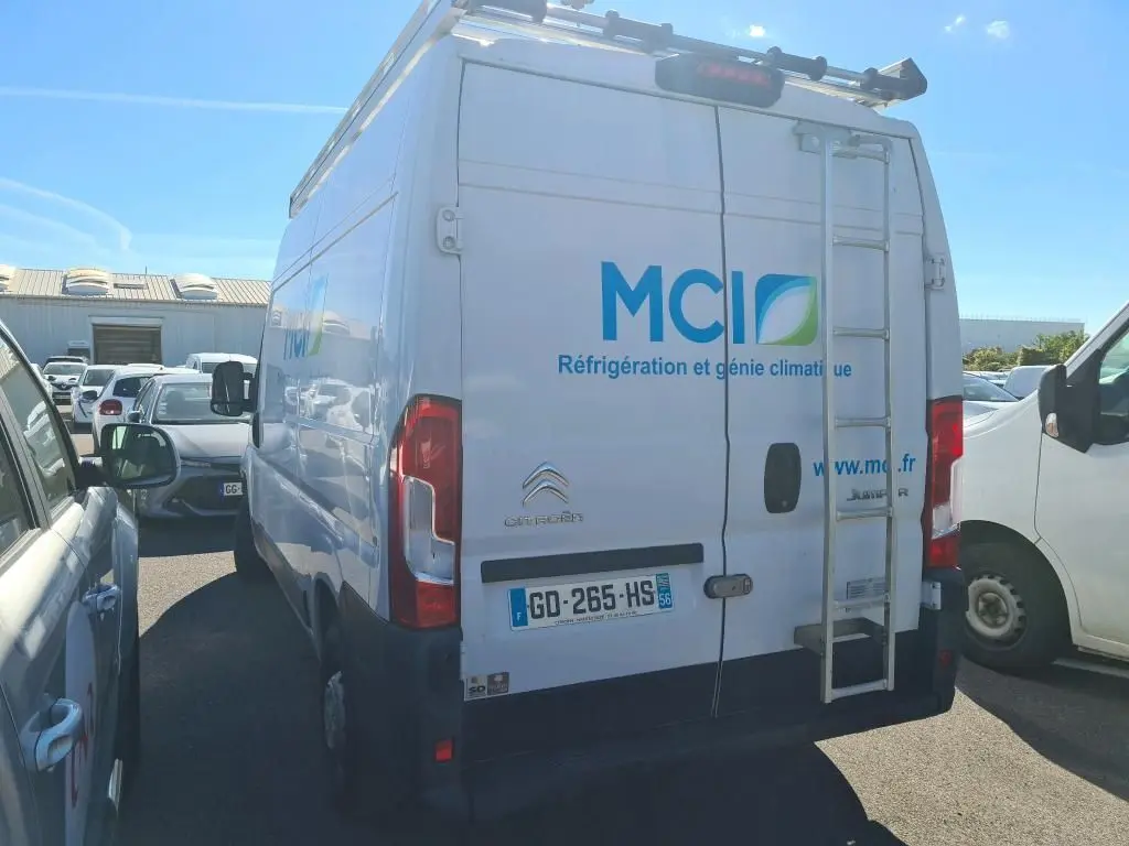 Vue arrière d’un Citroën Jumper blanc avec échelle et marquage MCI sur porte arrière, stationné en extérieur.