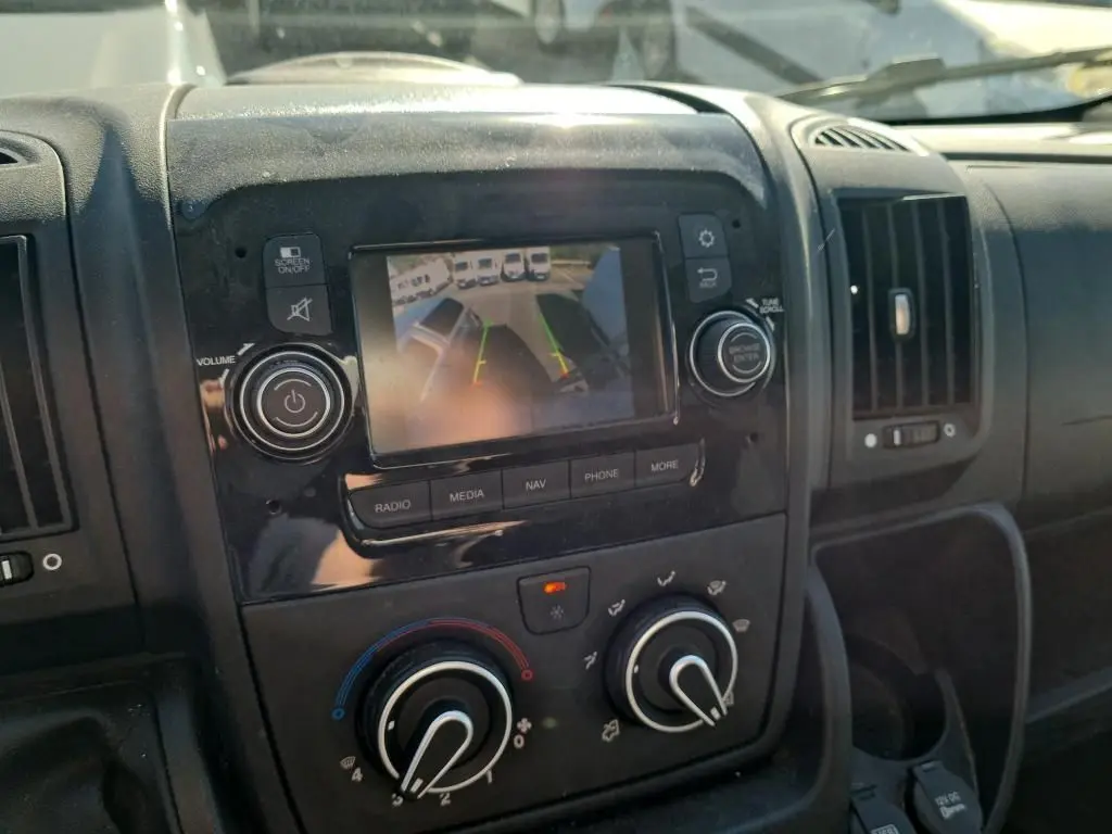 Vue rapprochée de la console centrale du Citroën Jumper blanc, écran de caméra de recul et commandes climatisation visibles.