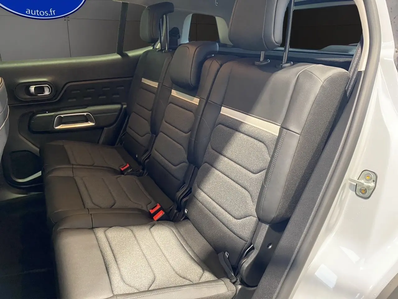Vue intérieure sur la banquette arrière noire et grise du Citroën C5 Aircross blanc, porte arrière droite ouverte.