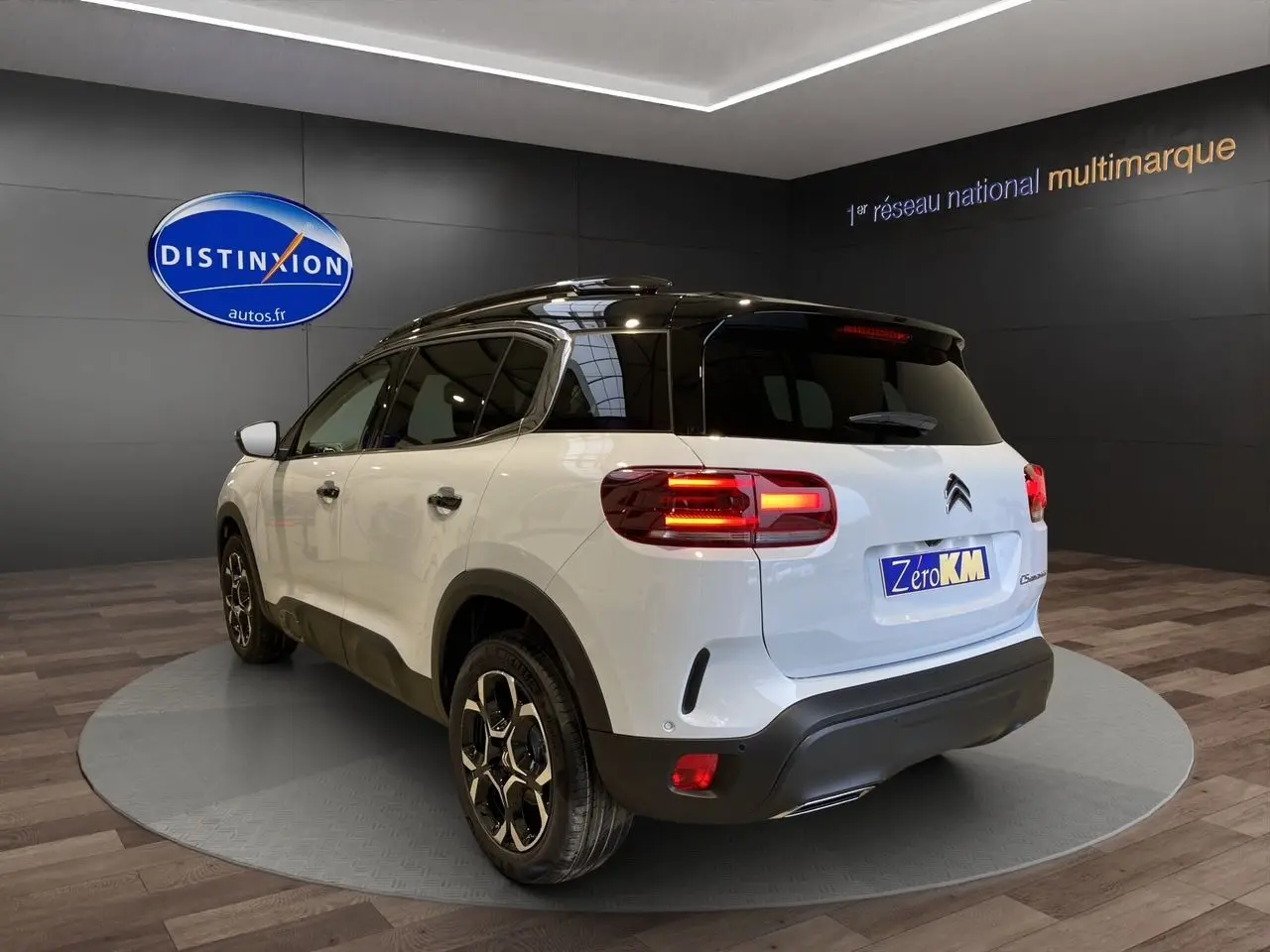 Vue 3/4 arrière droite du Citroën C5 Aircross blanc et noir 2024 avec feux allumés en showroom.