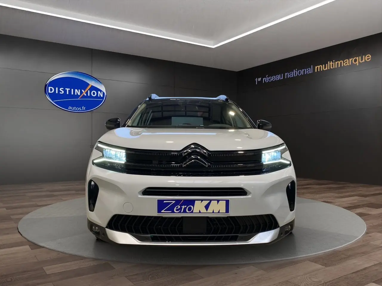Vue frontale d'un Citroën C5 Aircross blanc et noir 2024 avec phares LED allumés en showroom.