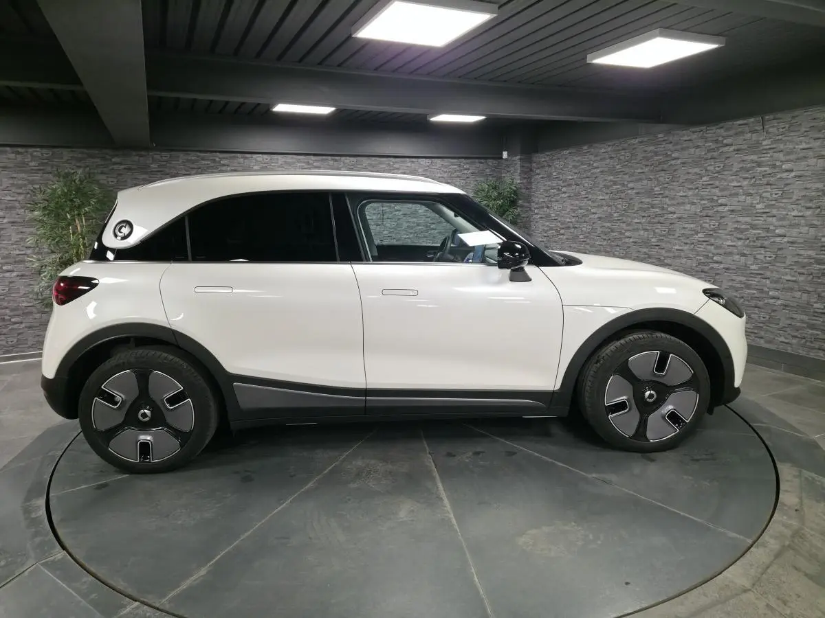 Vue de profil côté gauche d'une Smart #1 électrique blanche avec jantes spécifiques et toit blanc contrasté.