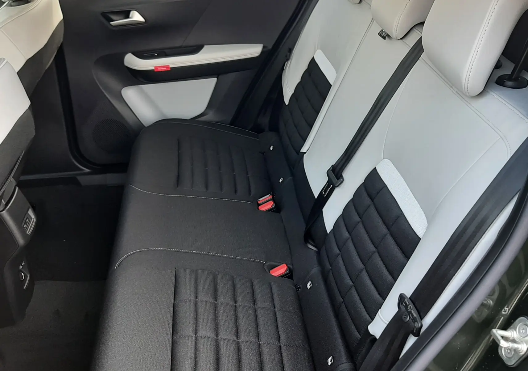 Vue intérieure arrière côté droit du Citroën C3 Aircross hybride 2026, sièges bicolores noir et blanc avec ceinture de sécurité.