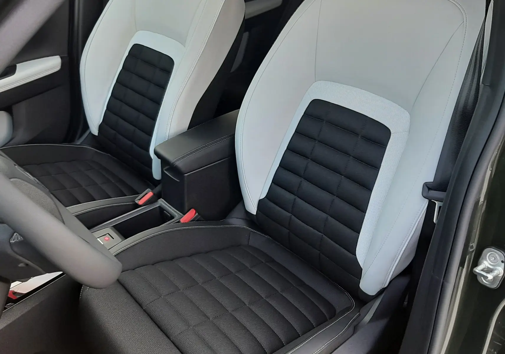 Vue rapprochée des sièges avant bicolores noir et blanc du Citroën C3 Aircross hybride 2026, porte ouverte côté droit.