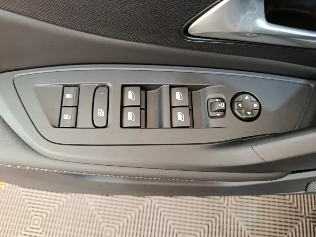 Panneau de commandes des vitres et rétroviseurs côté conducteur de la Peugeot 308 gris foncé, vue rapprochée intérieure.