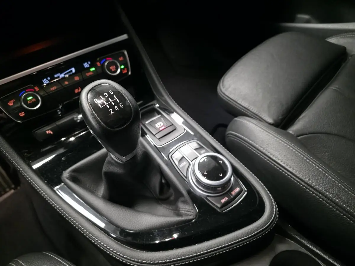 Gros plan sur la console centrale noire avec levier de vitesses manuelle et commandes iDrive d'une BMW Série 2 Gran Tourer.