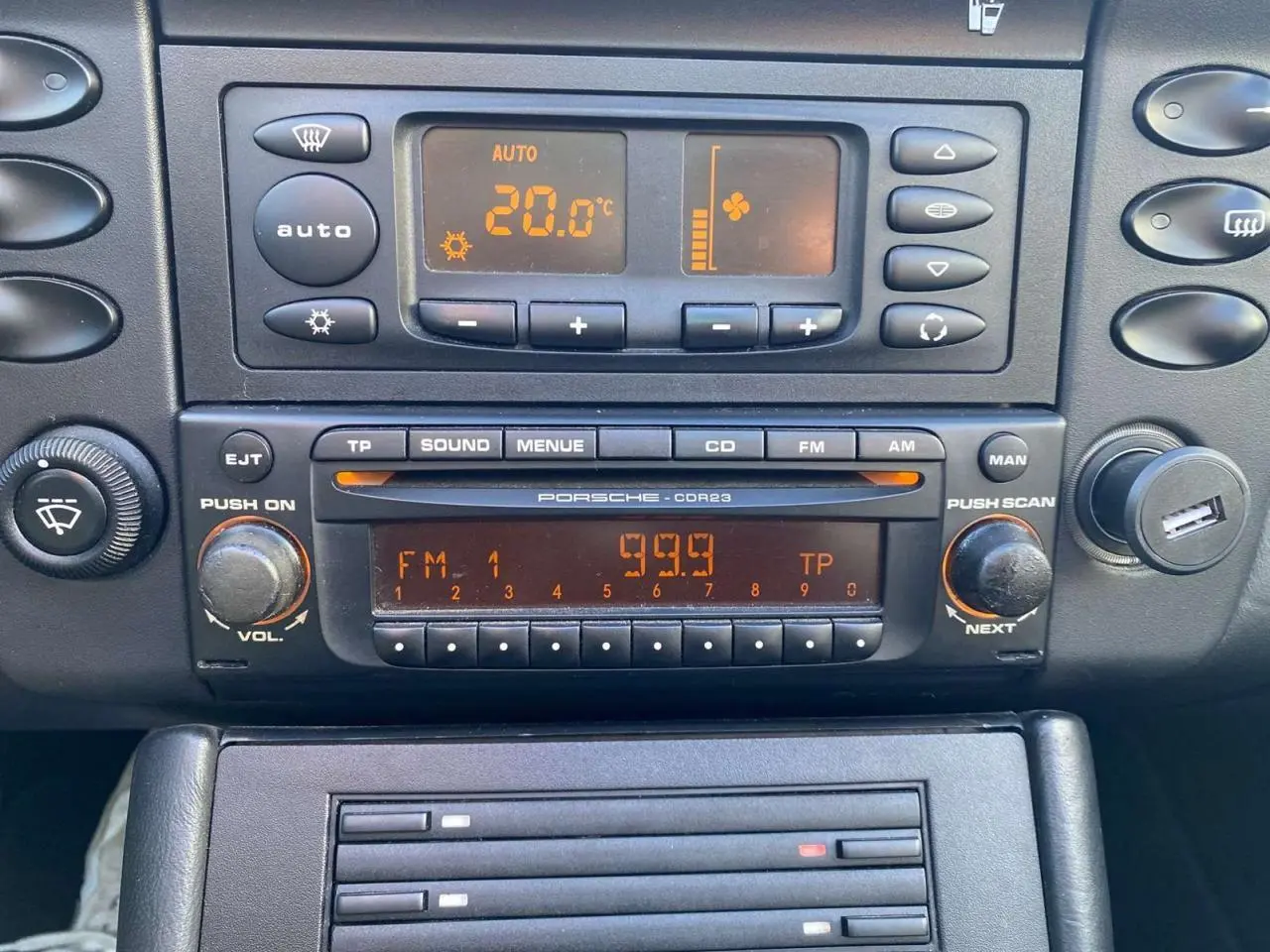 Tableau de bord de Porsche 911 Targa 2004 en gris foncé, vue rapprochée sur la radio et la climatisation digitale.