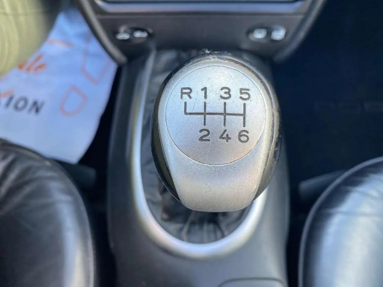 Gros plan sur le levier de vitesses manuel argenté dans l'habitacle noir d'une Porsche 911 Targa gris foncé de 2004.