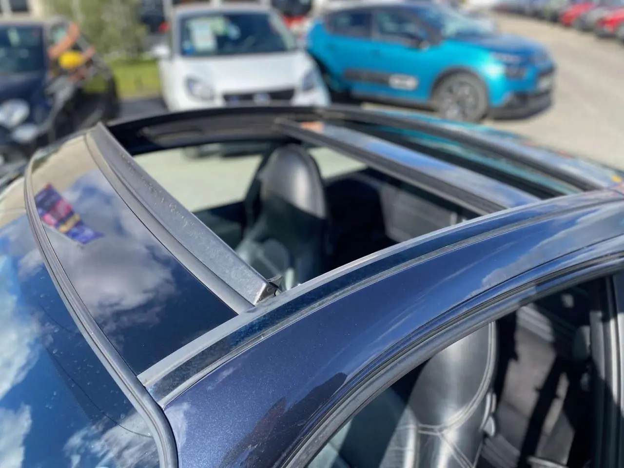 Vue rapprochée du toit ouvrant d'une Porsche 911 Targa 3.6i gris foncé de 2004, intérieur cuir noir visible.