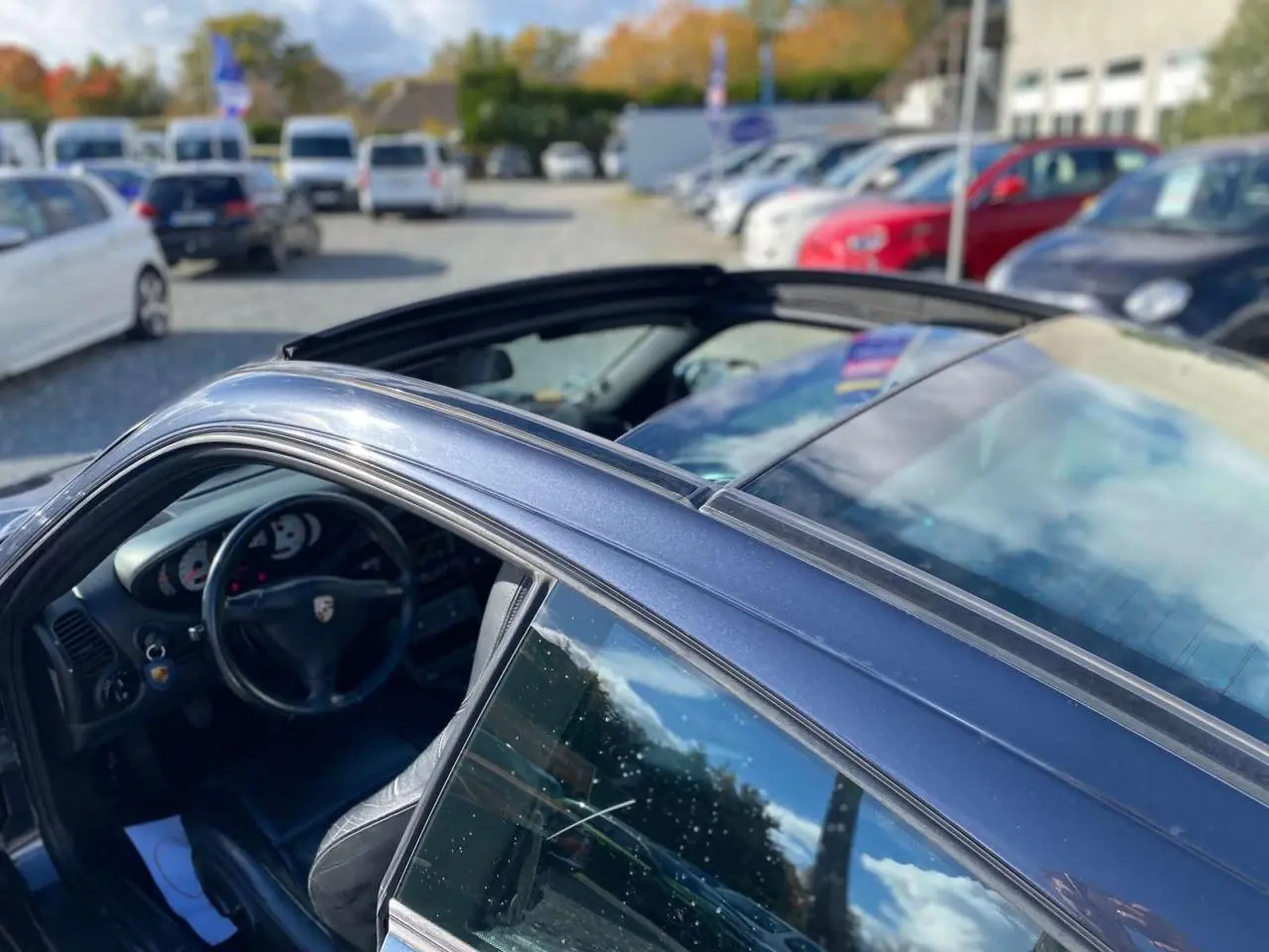 Vue 3/4 côté gauche d'une Porsche 911 Targa 3.6i gris foncé 2004 avec toit ouvert et intérieur visible.