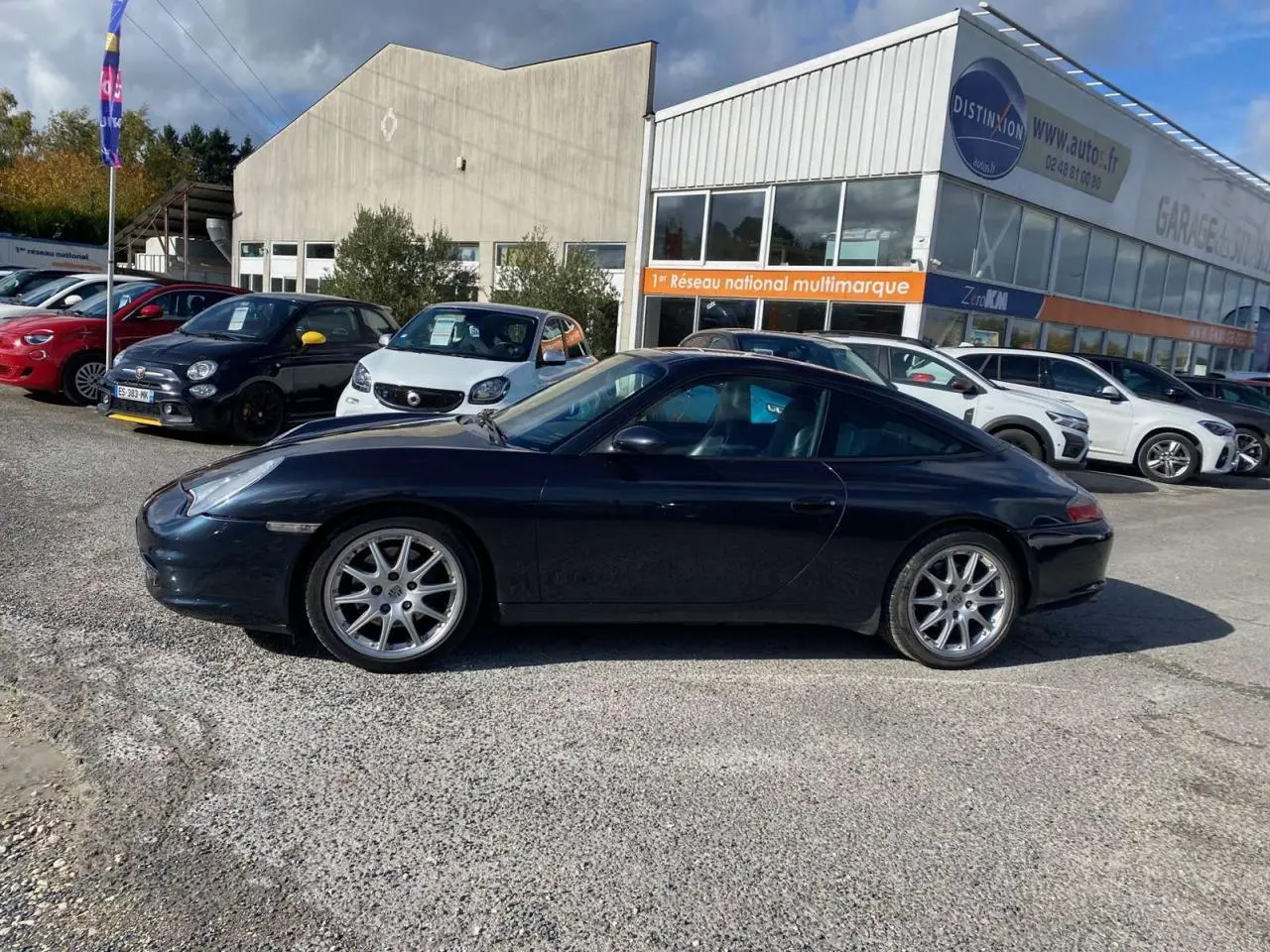 Profil côté gauche d'une Porsche 911 Targa 3.6i gris foncé de 2004 garée en extérieur sur un parking.