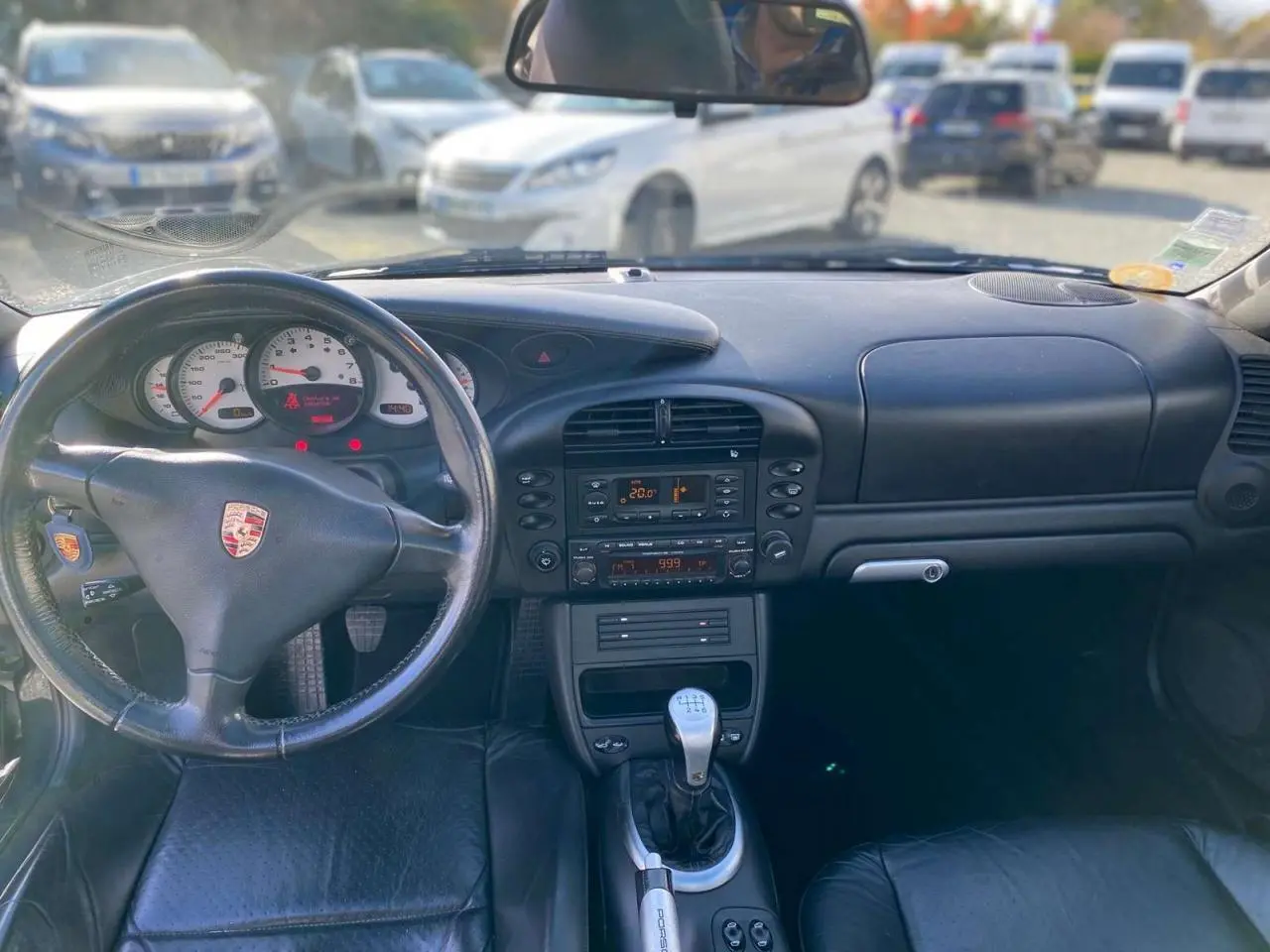Vue intérieure avant du tableau de bord noir et volant Porsche avec levier de vitesse manuelle d'une 911 Targa gris foncé de 2004.