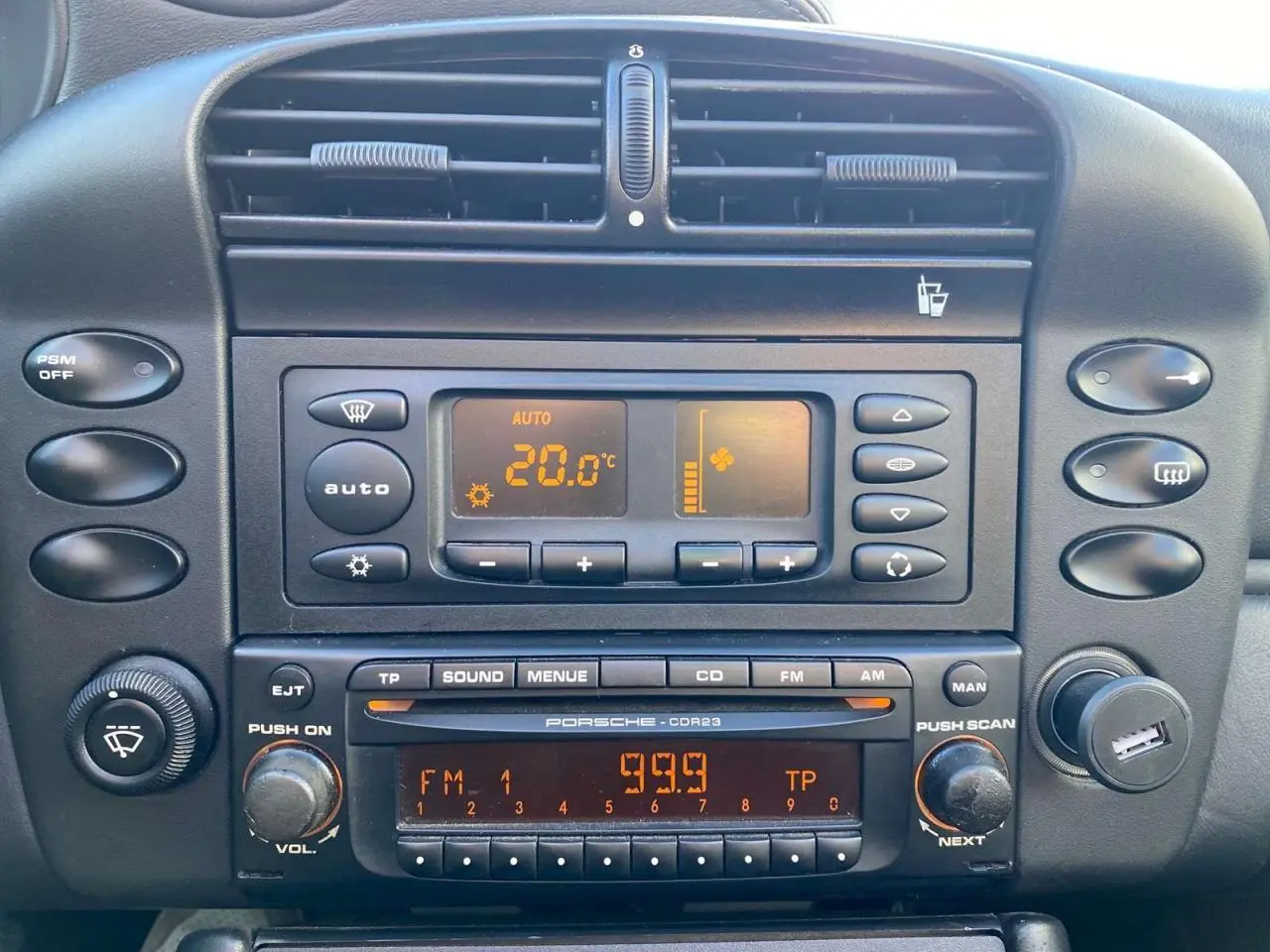 Vue rapprochée du tableau de bord noir du Porsche 911 Targa 3.6i 2004 avec commandes clim et radio d'origine.