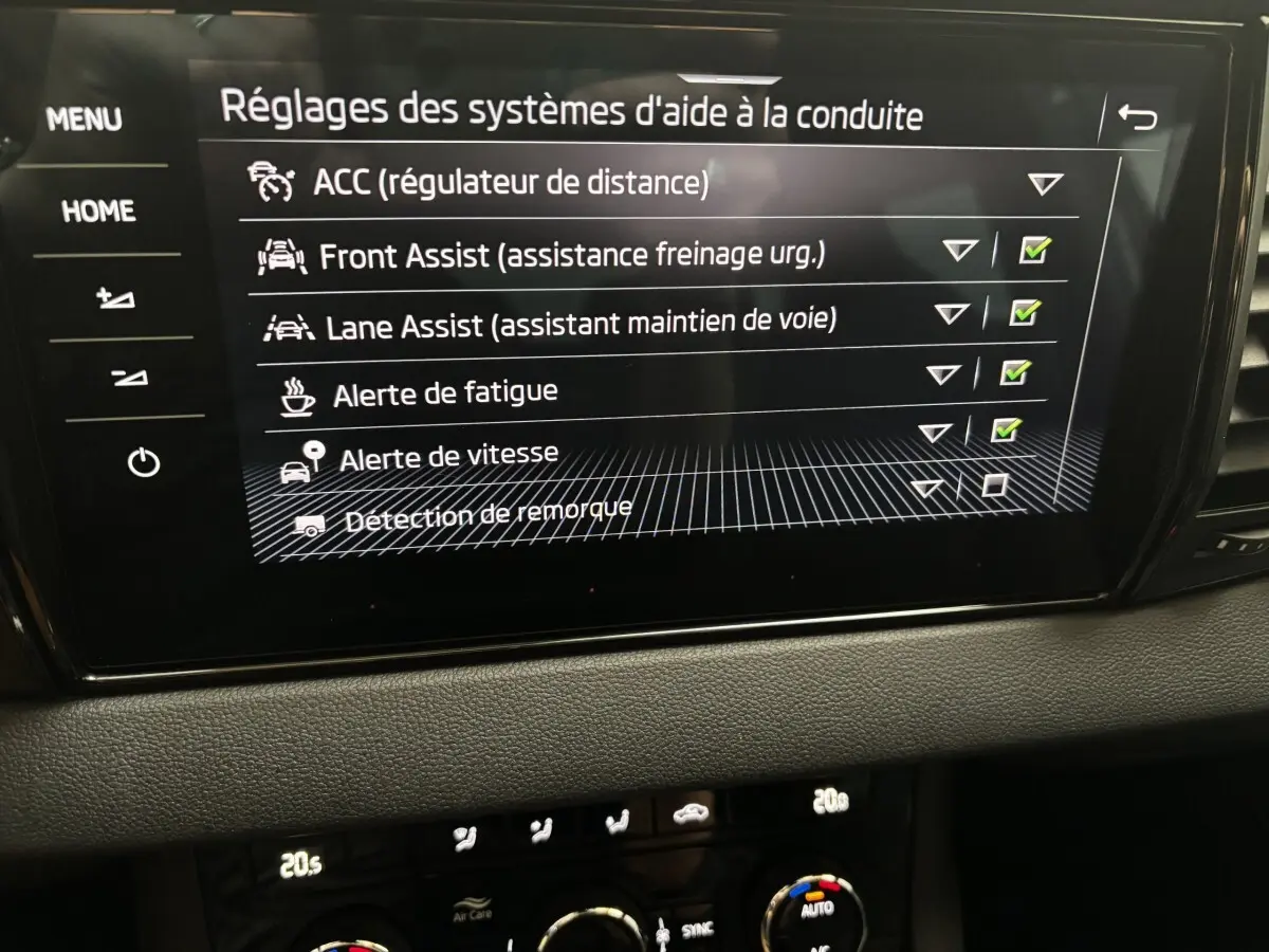 Écran tactile central du Skoda Karoq 2025 affichant les réglages des aides à la conduite dans un intérieur noir.