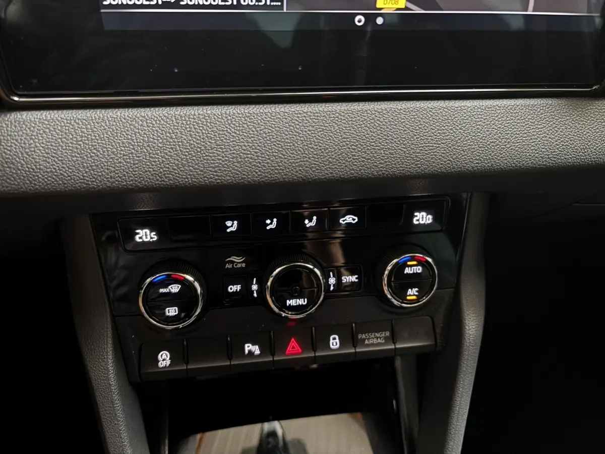 Gros plan sur la console centrale noire du Skoda Karoq 2025 montrant les commandes de climatisation digitale et boutons fonctionnels.